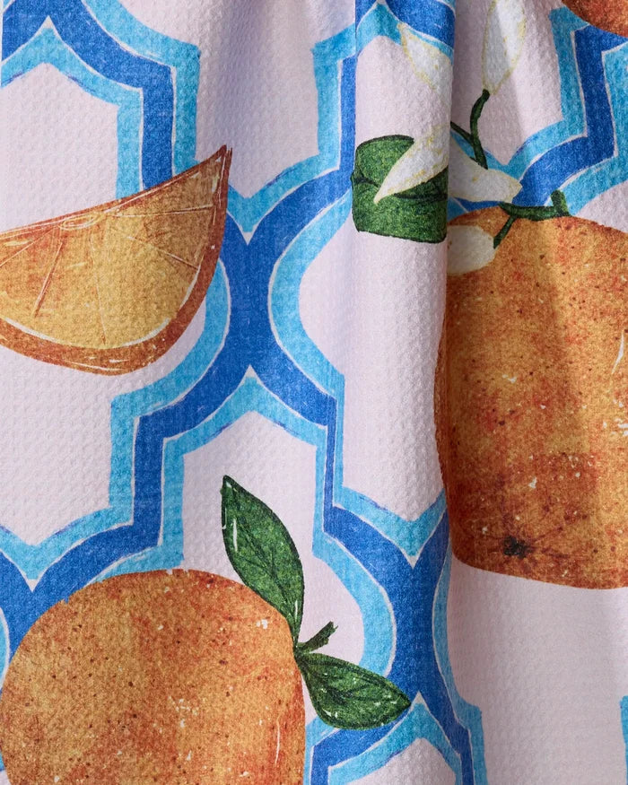 Close-up of the Pascale Dilger "Orange Trellis" absorbent dish towel, featuring oranges, slices, and green leaves on a white background with a blue trellis pattern.