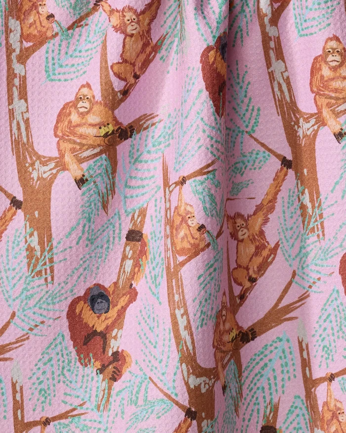 Orangutan Clan tea towel by Elisabeth Wing features orangutans swinging and sitting on leafy brown branches against a light pink background. The textured, gathered fabric adds charm to your kitchen décor.