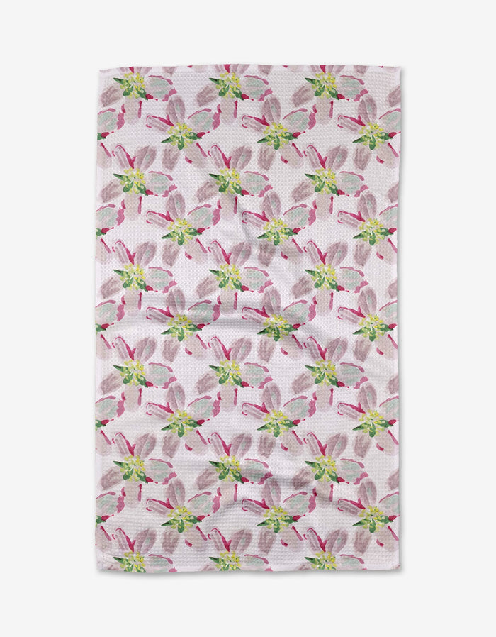 The Orchard in Bloom tea towel from Ania Zwara Art features a white textured surface with evenly spaced stylized floral designs in pink, green, and gray. Made from ultra-absorbent recycled materials for eco-friendly use.