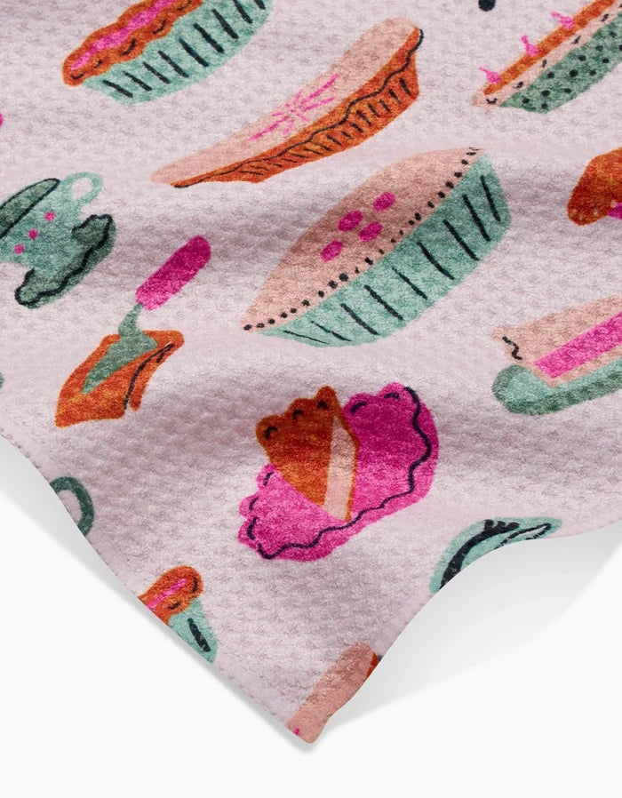 The Orla Bar Towel by Amy MacCready features a textured pink design with colorful pie, teacup, fork, and pie slice illustrations in green, pink, purple, and orange—all crafted from durable Geoweave fabric.