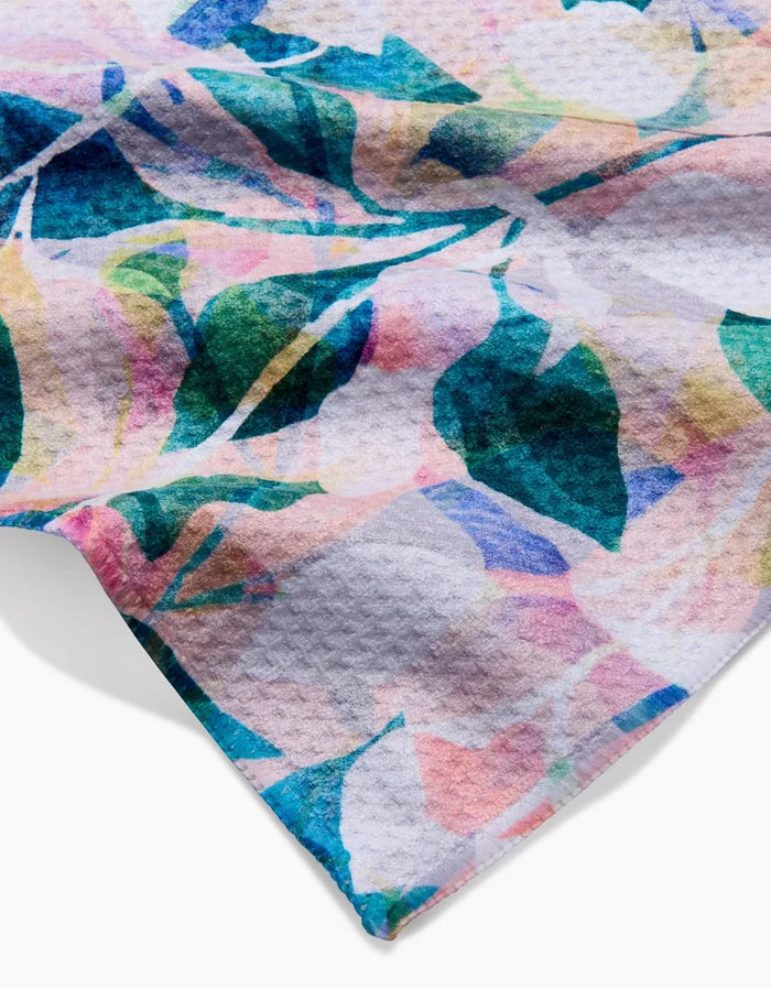 A close-up of the Painted Foliage Bar Towel by Rachel Parker, showcasing a colorful abstract floral design with blue, green, pink, and yellow shapes on textured white Geoweave fabric.