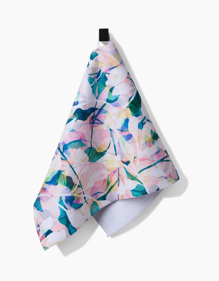 The “Painted Foliage” Bar Towel by Rachel Parker hangs on a black loop against a white background, featuring a pastel floral Geoweave fabric with watercolor-style pink, blue, yellow, and green leaves and flowers.
