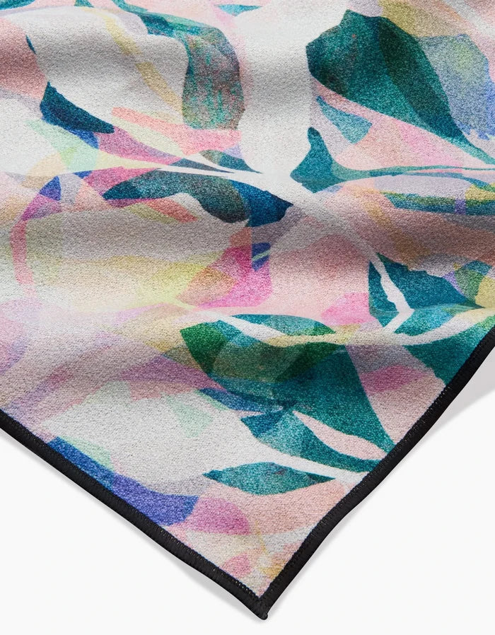 A close-up of the Painted Foliage beach blanket by Rachel Parker, made from recycled materials with an abstract, painterly design in pastel pinks, yellows, blues, and greens and finished with a black-edged hem.