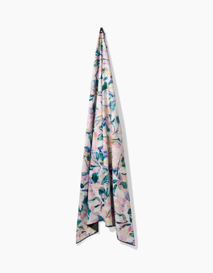 The Painted Foliage fabric by Rachel Parker, made from recycled materials and featuring a pastel floral pattern, hangs vertically from a hook against a plain white background.