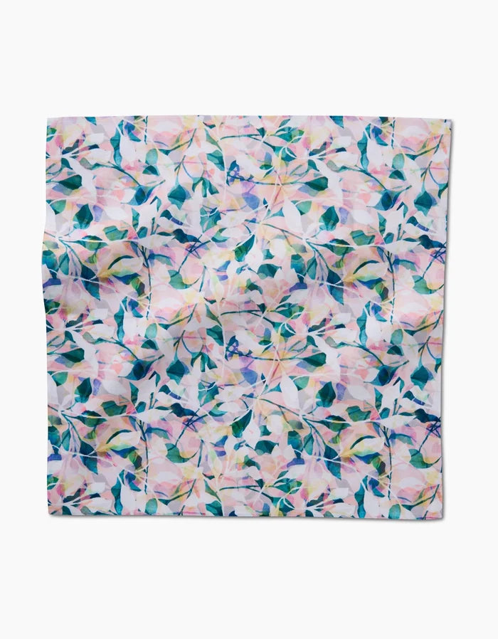 Painted Foliage by Rachel Parker is a square Geosuede fabric napkin featuring a pastel floral pattern in pink, green, and blue on white. The abstract leaves and flowers lend a soft, delicate touch—great for eco-friendly table settings.
