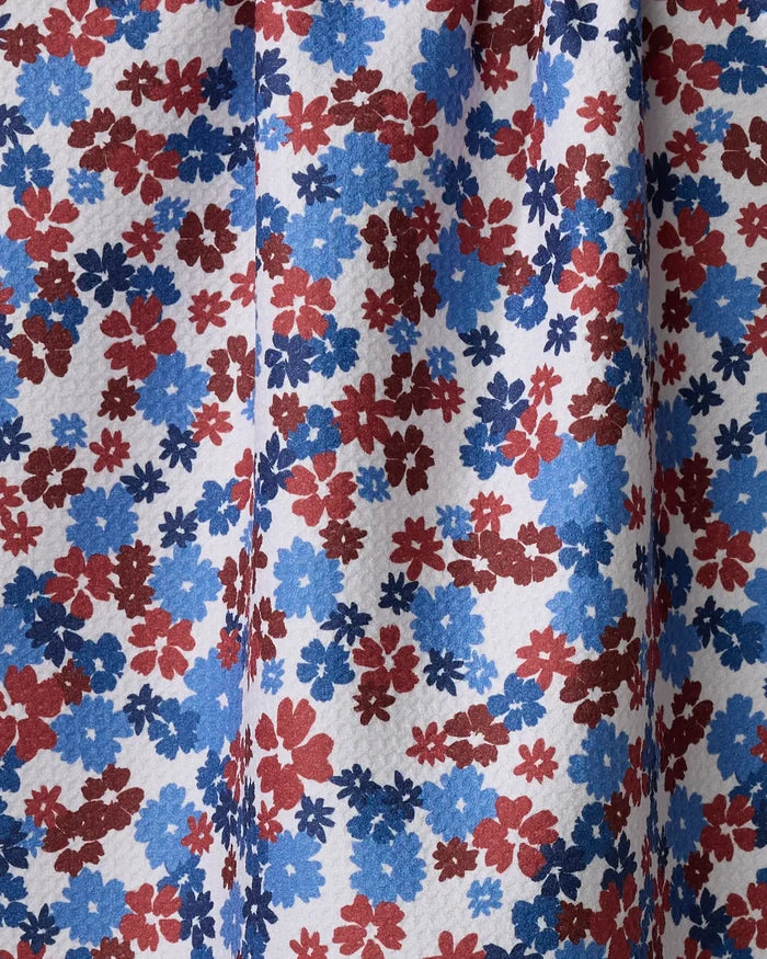 Close-up of the ultra-absorbent "Painted Petals" kitchen towel by Ashley Celena, showing its dense red, blue, and dark blue floral pattern on white recycled fabric with visible texture and gentle vertical folds.