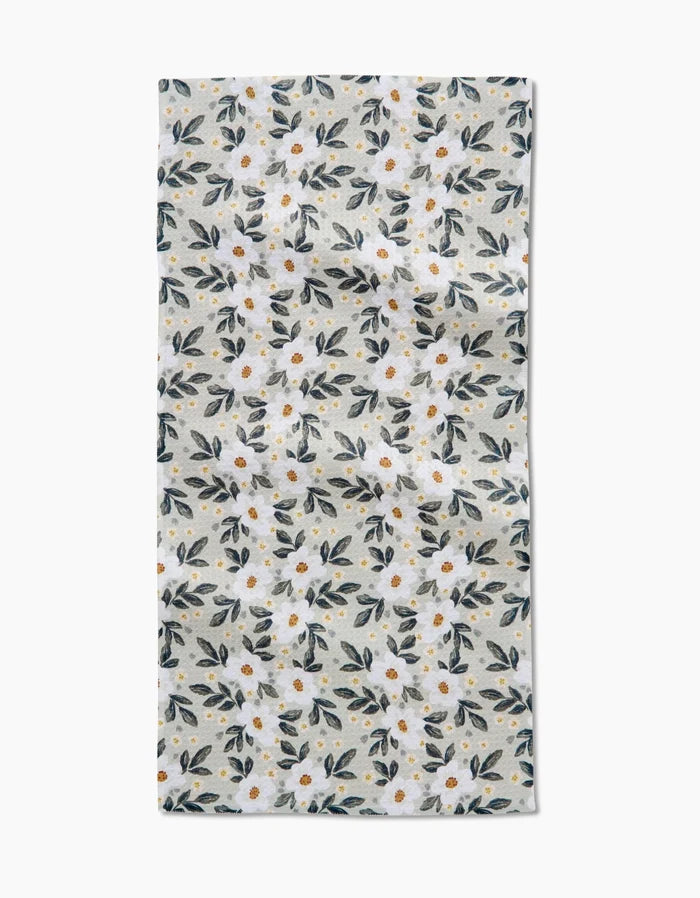 The Painted Spring Flowers Bar Towel by Teri the Butter features a white, rectangular design with small white flowers, yellow centers, and blue-green leaves on a light grey background. Made from durable Geoweave fabric.