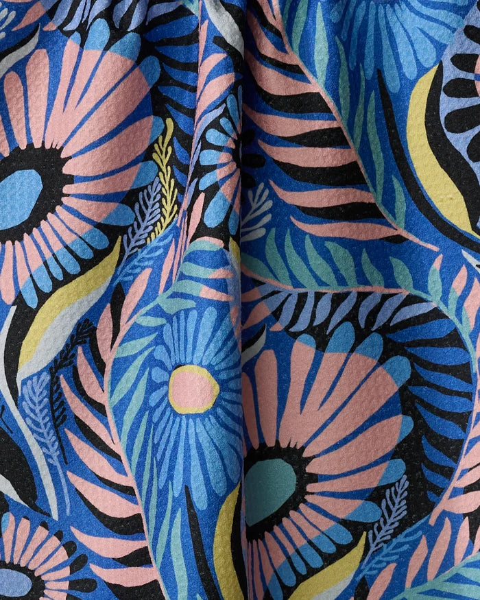 The Palm Beach kitchen towel by Masha Volnova features a colorful, textured fabric with bold abstract flowers in blue, pink, yellow, and black plus leafy accents—perfect for adding vibrant style to any space.