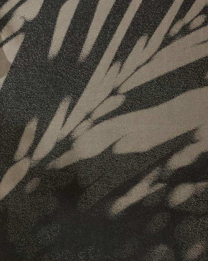 The GEOMETRY Palm Shadow yoga towel features an abstract black and beige pattern reminiscent of animal print or filtered sunlight, with a non-slip surface for secure practice.