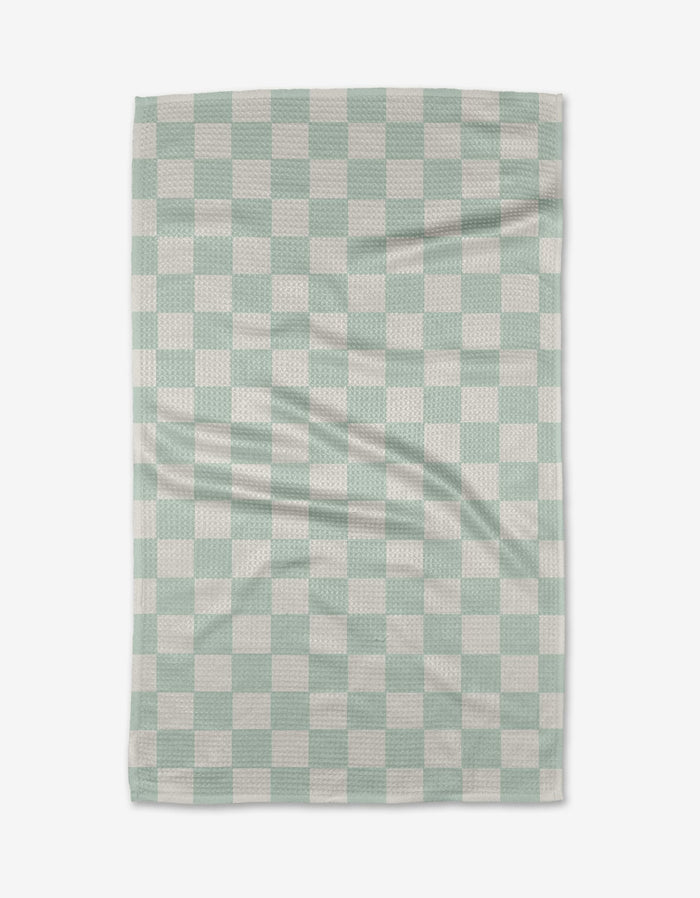 The Pastel Picnic blanket by Sweet Simple Vegan is a rectangular throw made from recycled materials, shown flat with gentle folds. It features a light green and white checkered grid pattern with evenly sized squares.