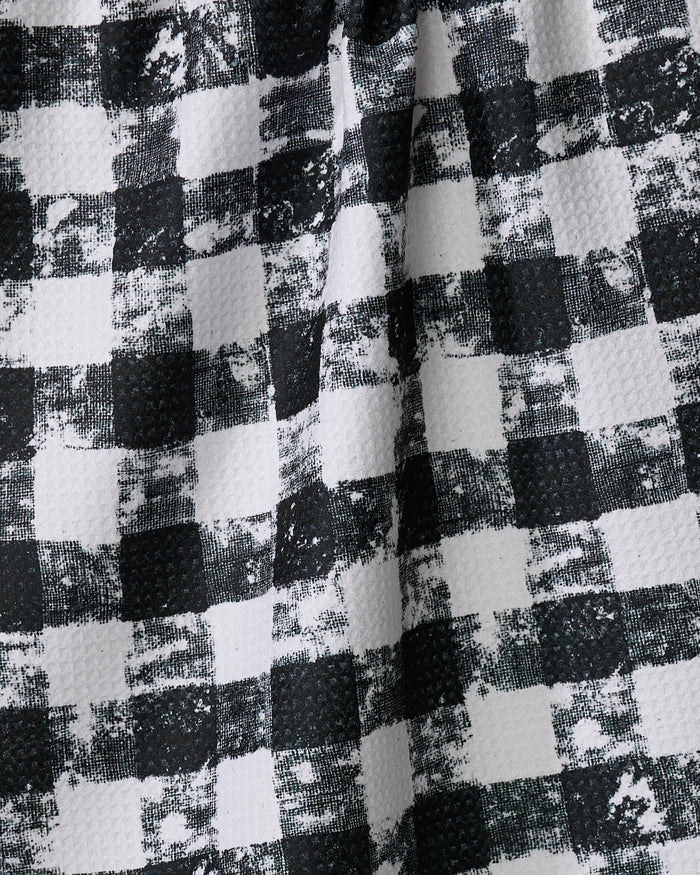 Close-up of Patch Ash by Geometry, showing its black-and-white checkered textured fabric with a worn, grid-like pattern and visible creases, reminiscent of a recycled kitchen towel.