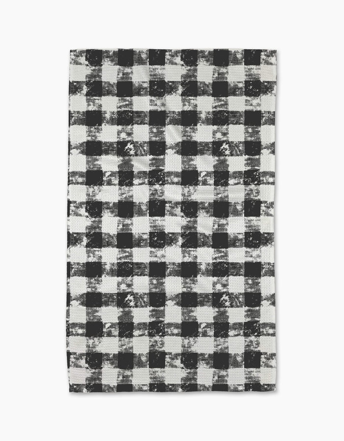 The Geometry Patch Ash tea towel features a black and white buffalo plaid pattern with a distressed, textured look on a white background.