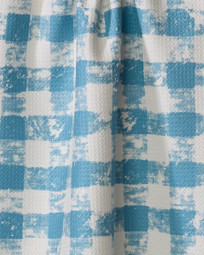 A close-up of Patch Denim by Geometry shows blue and white checkered fabric with a textured, painterly look and vertical folds, typical of a recycled kitchen towel.