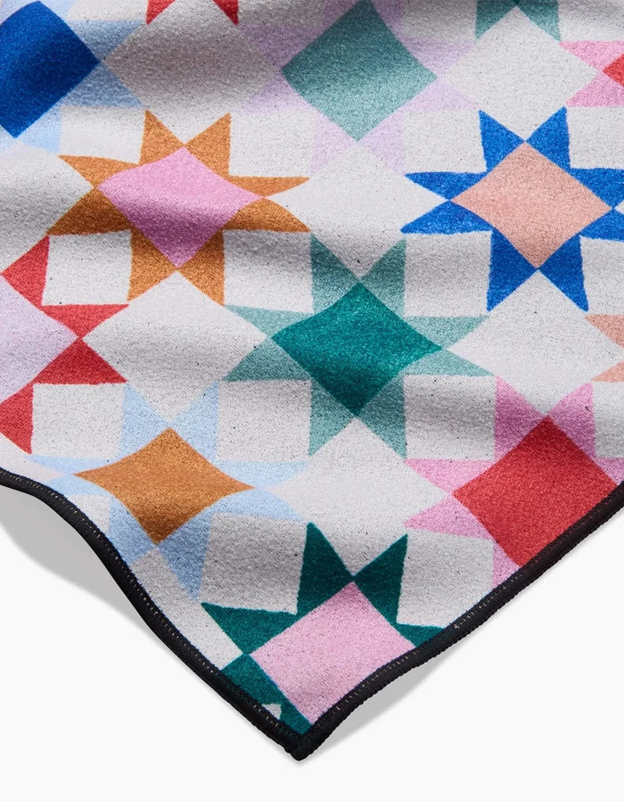 Patchwork Picnic by Brittany Jepsen is a colorful quilt with geometric star patterns in pink, blue, green, orange, and red, bordered in black—expertly crafted from recycled materials for eco-friendly style.