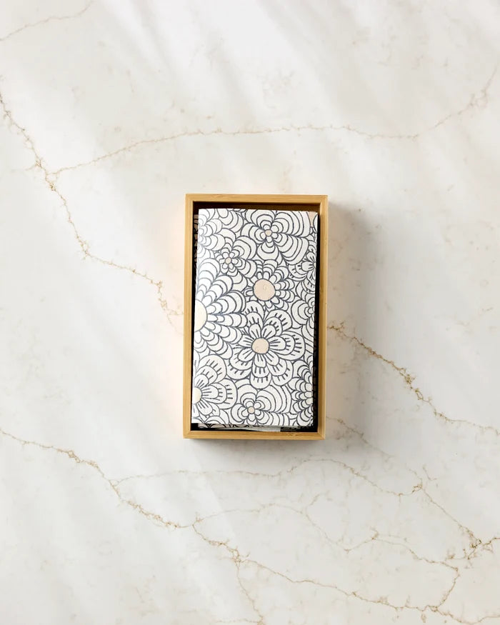 The Paulette by Amy MacCready is a rectangular box with a black and white floral lid, ideal for storing eco-friendly kitchen towels or sustainable cleaning cloths, and looks elegant on any light marble surface.