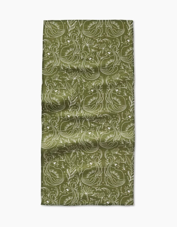The Amita Nair Peacock Blooms Bar Towel is green and rectangular, made from Geoweave fabric, with a detailed white floral and leaf pattern. It appears slightly wrinkled and lies flat on a plain white background.