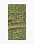 The Amita Nair Peacock Blooms Bar Towel is green and rectangular, made from Geoweave fabric, with a detailed white floral and leaf pattern. It appears slightly wrinkled and lies flat on a plain white background.