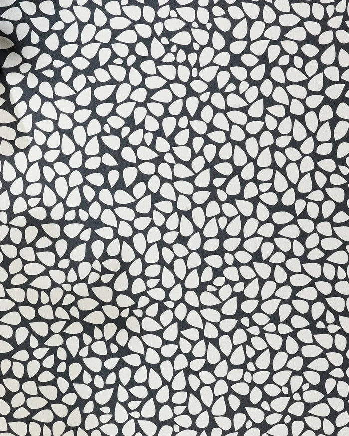 The Pebbles yoga towel by Marina Solodka features an abstract pattern of white pebble shapes on black, offering stylish texture and a dense design for enhanced grip and non-slip performance during your yoga practice.