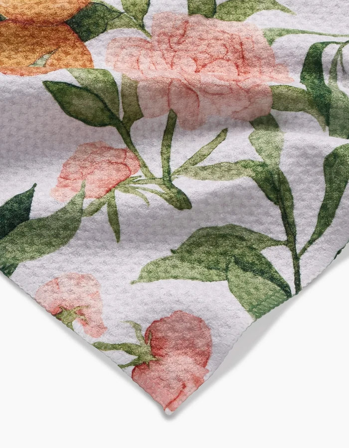 A close-up of the Peony For Your Thoughts Aubrey Fairchild Geoweave bar towel, showcasing a white textured ultra-absorbent fabric with a floral pattern of pink and orange flowers with green leaves.