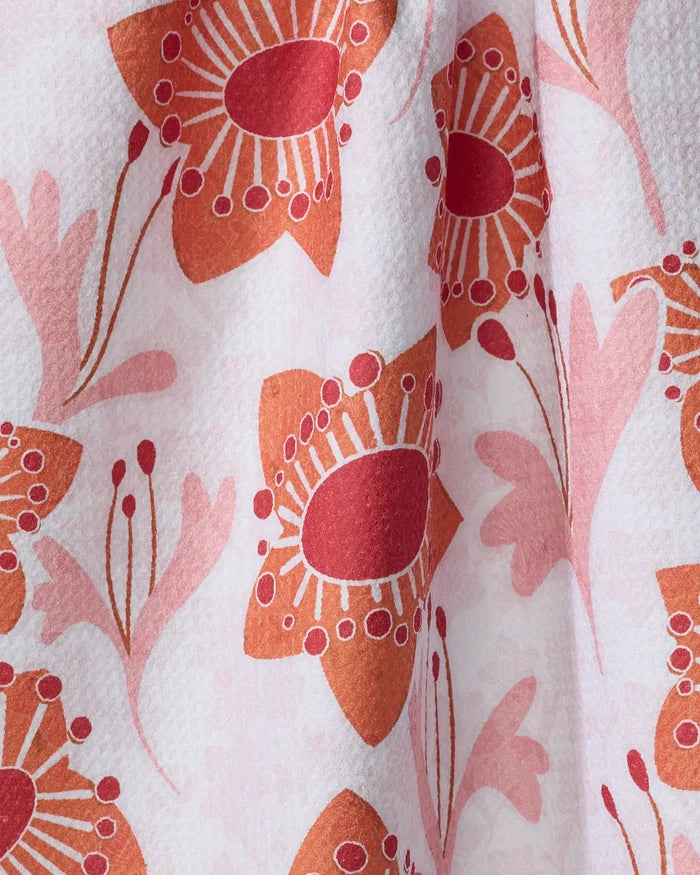 Close-up of the Whitney Urquhart "Petal Paradise" absorbent dish towel, showcasing a vibrant floral pattern in red, orange, and pink on a white textured background.