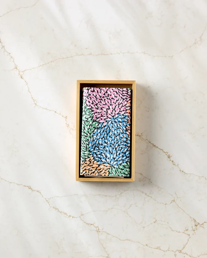 A rectangular box of Rachel Parker's Petal Pen sits on a light marble surface, its packaging adorned with colorful petal-like patterns in pink, blue, green, and tan—a stylish addition to any eco-friendly workspace.