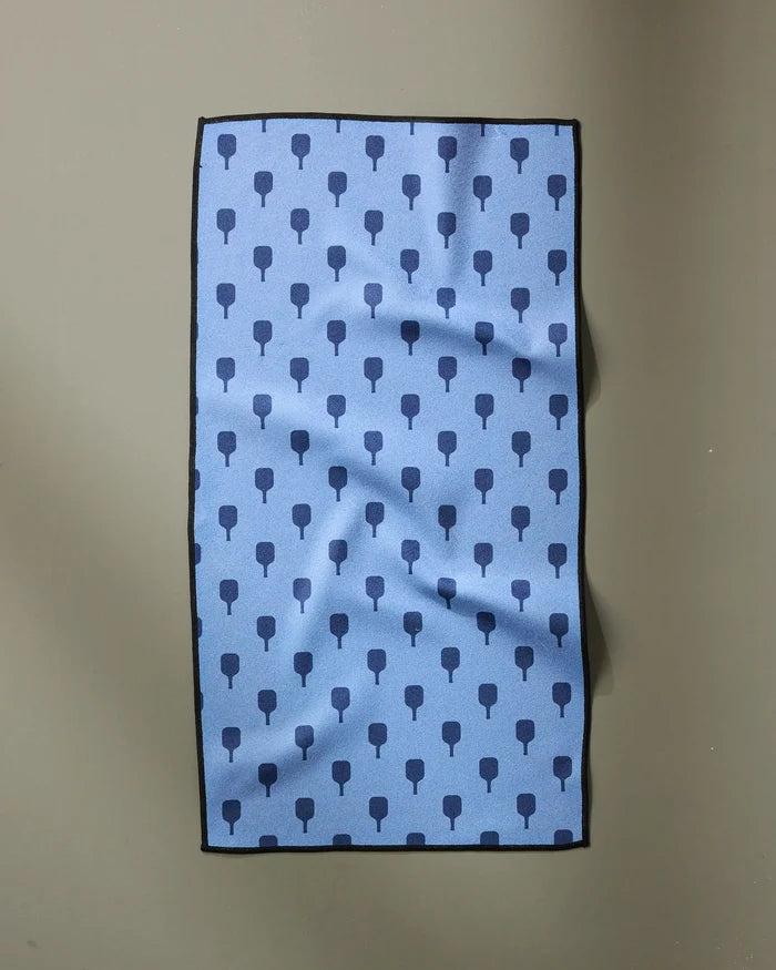 The Modern Dad’s “Pickle Ball Anyone” is a rectangular blue fitness towel with a dark blue tree-like pattern, black edges, and slight wrinkles. Ultra-absorbent for quick drying after workouts; shown on a plain gray background.