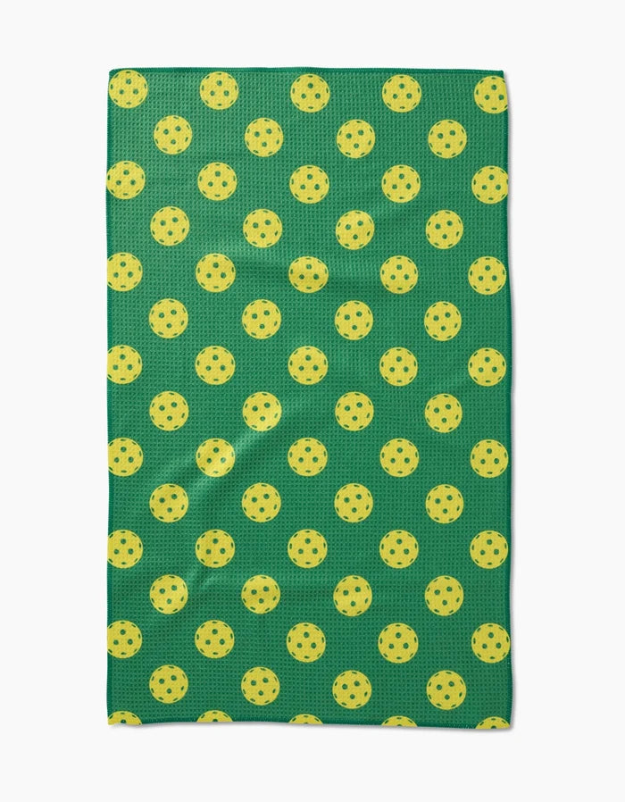 The GEOMETRY Pickleball tea towel is green, rectangular, made of Geoweave fabric, and features a pattern of evenly spaced yellow pickleballs.