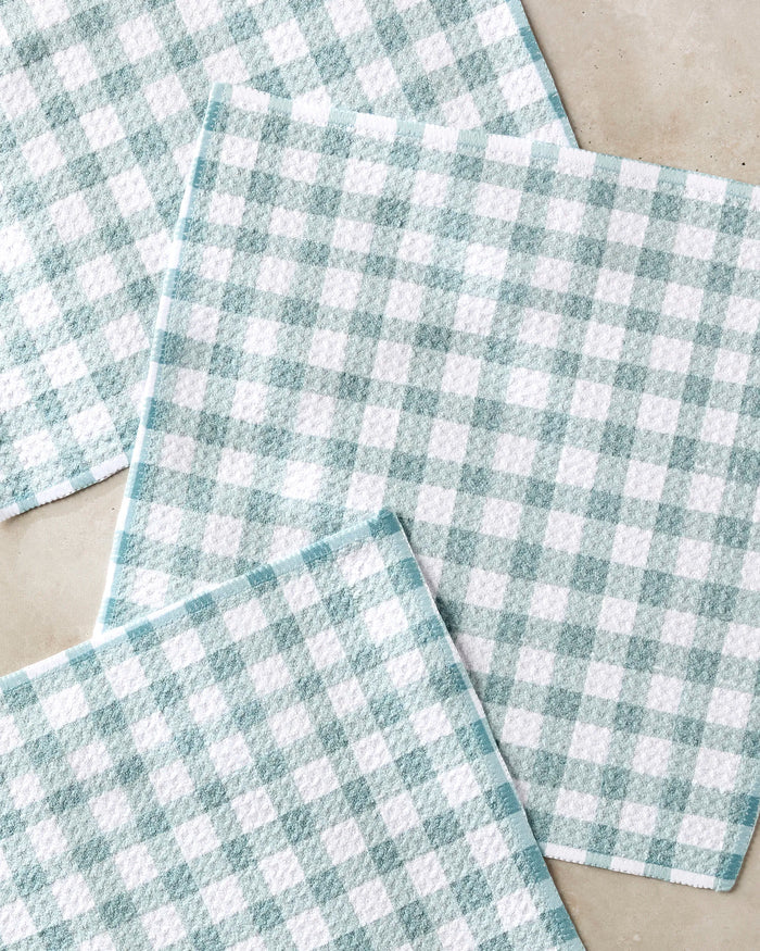 Three Picnic Gingham dish towels by Hufton Studio, featuring a light blue and white checkered pattern, are arranged overlapping on a light surface.