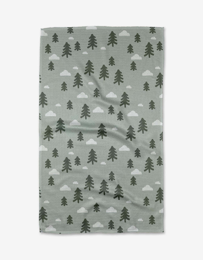 The Pine Forest Tea Towel by Coit Creative is a green, rectangular towel made from Geoweave™ fabric, featuring dark green pine trees and white clouds patterned across the surface.