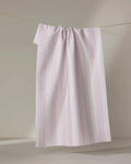 The Teri the Butter Pink Chevron Stripe ultra-absorbent towel hangs on a clothesline against a neutral beige background.