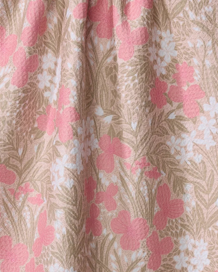 Close-up of Katie O'Shea's Pink Meadow kitchen towel, featuring a floral pattern with pink, white, and beige flowers and green leaves on a light beige background. The texture of the recycled material fabric is slightly visible.