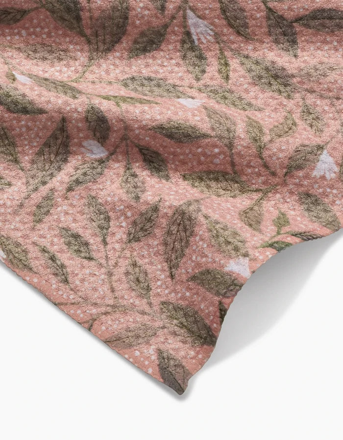 A close-up of the Katie OShea Pink Mint Leaves bar towel, featuring soft, textured pink Geoweave fabric with a green and white leafy botanical pattern and visible folds.