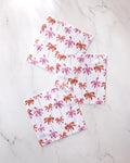 The GEOMETRY Pink Palms dishcloth set includes three super-absorbent towels, each adorned with pink and orange palm tree patterns on a white marble background.