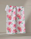 The "Pink Peony" tea towel by Elena Fay features a watercolor floral design with pink flowers, green leaves, and gold accents, displayed against a neutral background.
