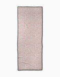 The Pink Scandi Flowers yoga towel by Katie OShea is rectangular, light pink with a white symmetrical floral pattern and a thin black border, shown flat on a white background.