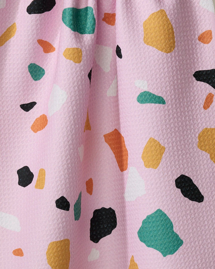 Close-up of Megan Roy's Pink Terrazzo kitchen towel—an eco-friendly pink textured fabric with a vibrant terrazzo pattern featuring irregular black, green, orange, yellow, and white shapes.