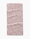 The Studio Jeannot Pixie towel is a rectangular, light pink bar towel with an abstract white dotted pattern, made from soft Geoweave fabric. Gentle creases add a plush, modern touch as it lays flat on a white background.