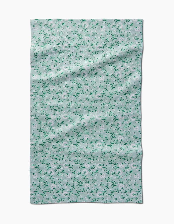 Plumbago Bloom by Danelys Sidron features a light blue Geoweave fabric with a pattern of small white flowers and green vines, shown flat with visible creases and folds.