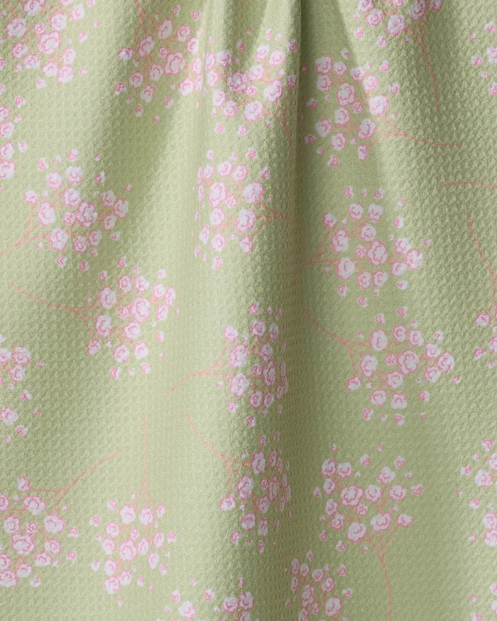 A close-up of Sarah Reed's Pocket of Posies: light green textured recycled kitchen towel fabric, accented with small pink and white flowers linked by delicate pink stems.