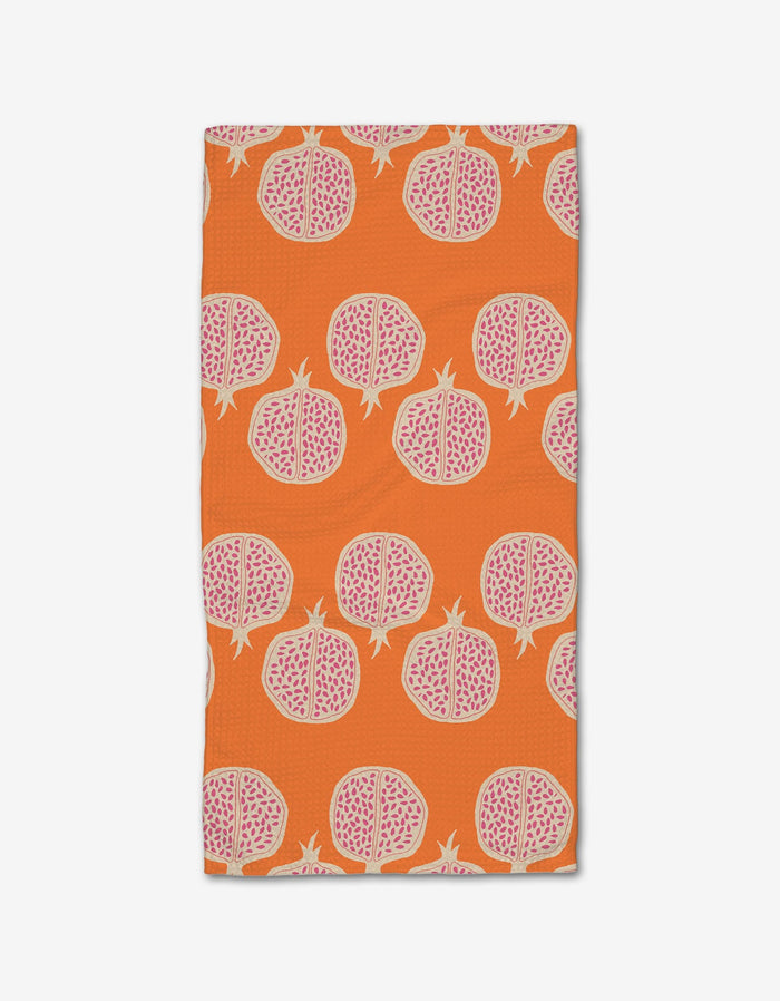 The Pomegranate Parade bar towel by Lizzie Clark features a vibrant orange Geoweave fabric with a repeating motif of halved pomegranates in pink and white.