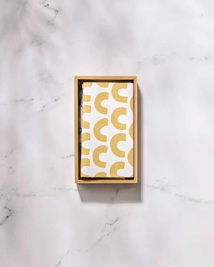 The GEOMETRY Pop Of Color rectangular wooden tray displays a white napkin featuring a repeating yellow crescent pattern, resembling reusable paper towels, resting on a white marble surface.