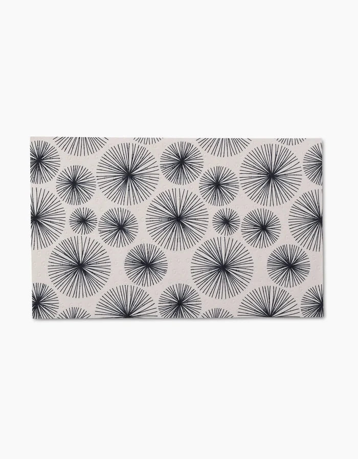The GEOMETRY Pop Of Color mat is rectangular with a white background and a repeating pattern of black starbursts in various sizes, crafted from post-consumer recycled materials for an eco-friendly touch.