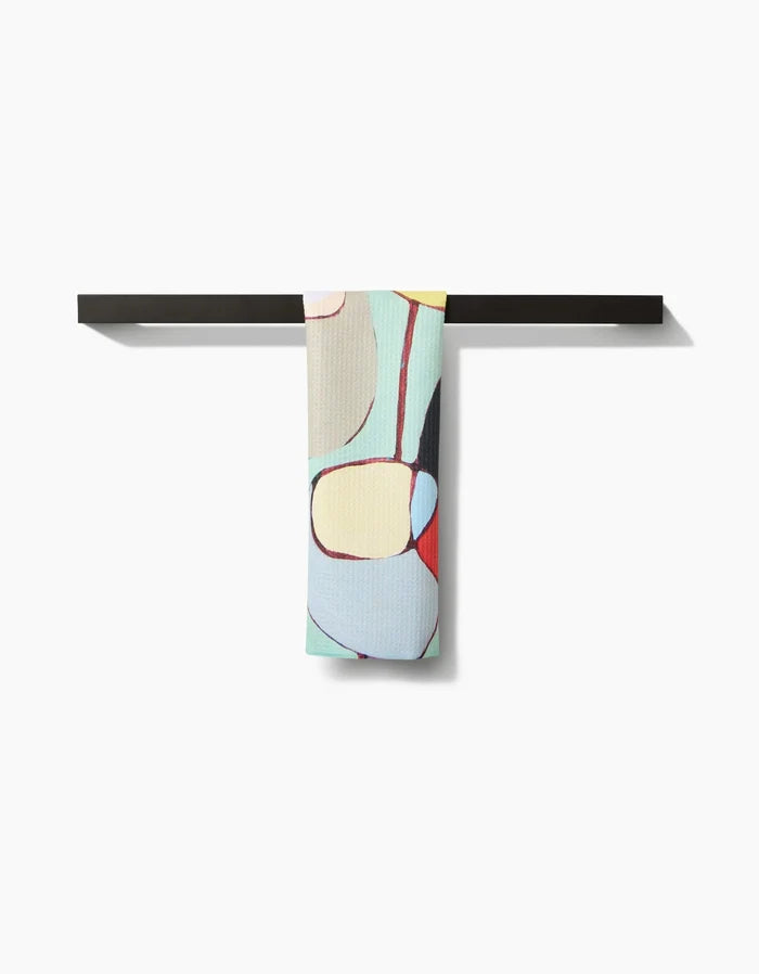 A modern black bar towel holder displays the Poppies on Mint towel by Rachel Austin, featuring a colorful abstract pattern on Geoweave fabric with curved pastel shapes against a white background.