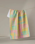 The Positive Vibes tea towel by Sareka Unique features a pastel geometric pattern in pink, yellow, blue, and green. Made from quick-drying recycled materials, it’s both stylish and practical—a colorful accent for any kitchen.
