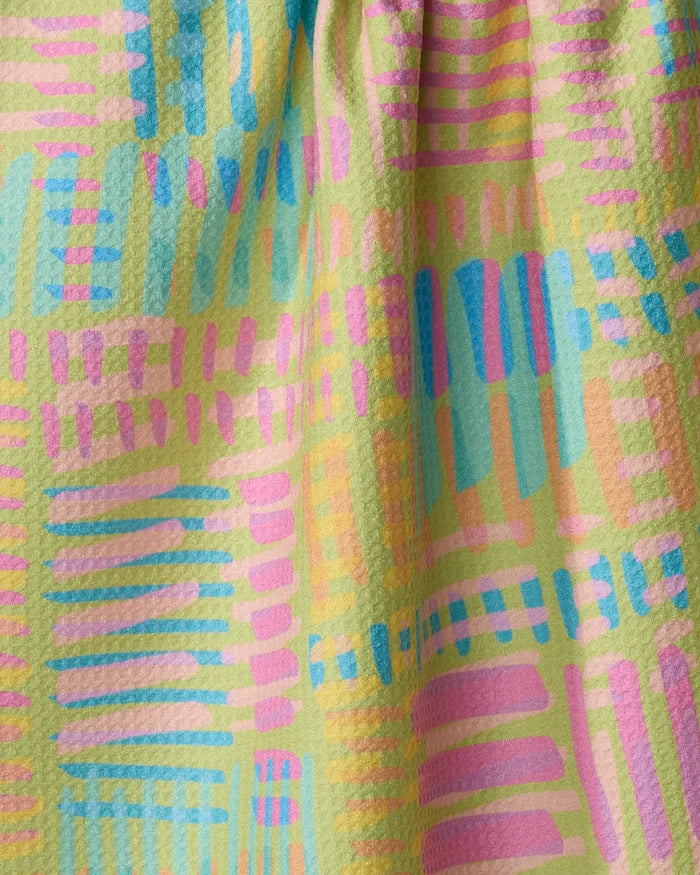 The Positive Vibes tea towel by Sareka Unique features a colorful abstract pattern with pastel brushstrokes in pink, blue, teal, and orange on light yellow textured fabric. Quick-drying with soft folds and a pebbled surface.