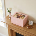 Pink pet photo urn with a photo of a dog on a wooden surface next to a vase and small dog figurine.