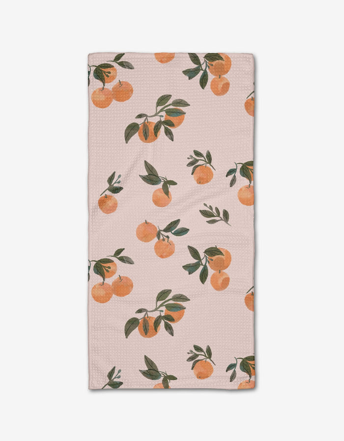 The Pretty In Peach bar towel by Janna Sue Design is a light pink, rectangular towel with a print of orange branches, green leaves, and clusters of oranges. Made from durable Geoweave fabric for excellent absorbency.