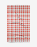 The Pretty in Pink Plaid tea towel by Charlie Rowan Designs is made from recycled materials, features a pink checkered pattern, and is shown flat with slight wrinkles on its quick-drying fabric.