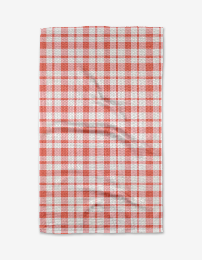 The Pretty in Pink Plaid tea towel by Charlie Rowan Designs is made from recycled materials, features a pink checkered pattern, and is shown flat with slight wrinkles on its quick-drying fabric.