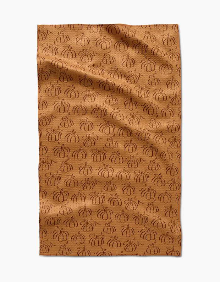 Aubrey Fairchilds Pumpkin Patchwork tea towel features a brown background with an all-over pattern of darker brown, outlined pumpkins, shown flat with subtle wrinkles.